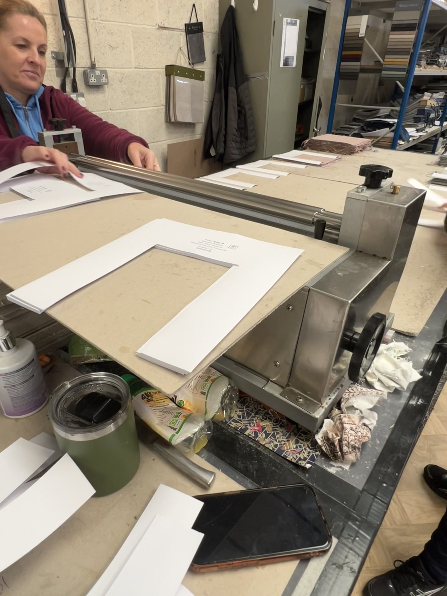 Maker feeding shaped white display boards through the workshop glue roller